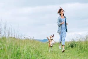 happy woman running with dog in field