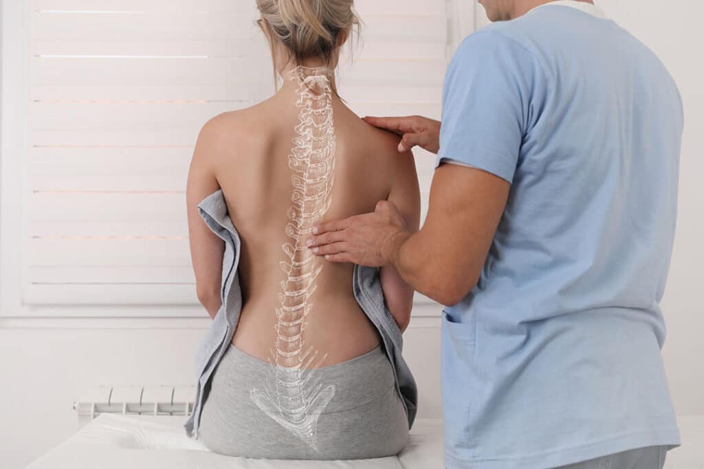 chiropractor checking woman's spine - spine wellness