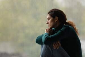 Woman looking out rainy window - Managing Mood Swings at AlignLife