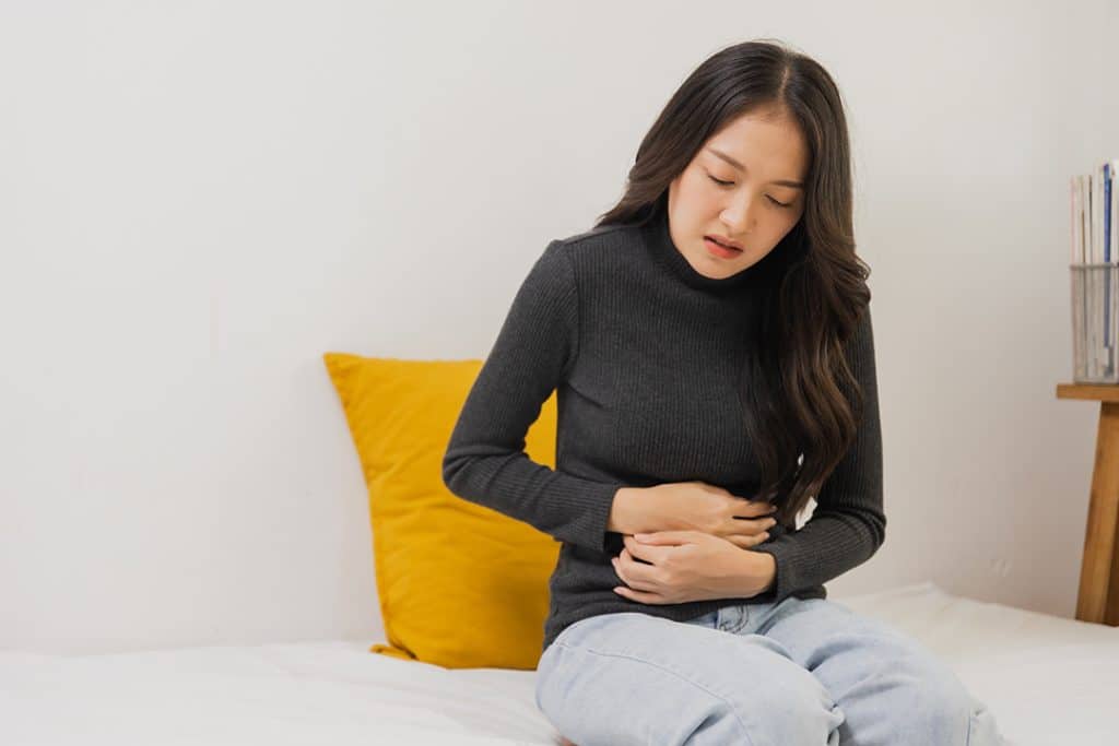 Woman holding stomach with gut issue - symptoms of bad gut health