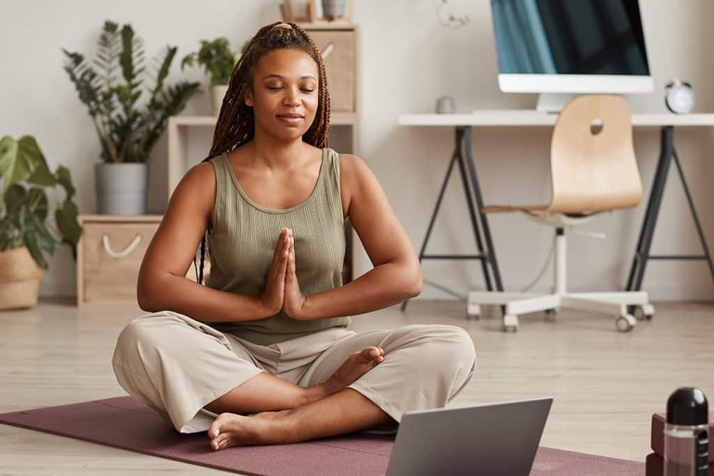 Woman meditating at home - How to Get Rid of Stress Belly