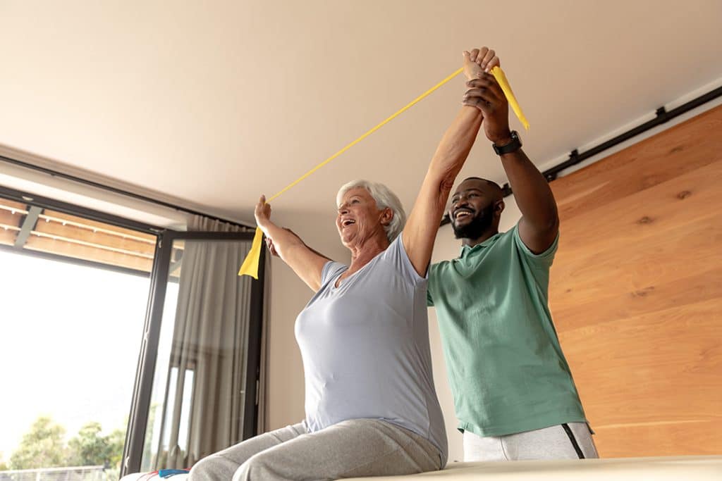 older woman working on strength and mobility in her back with resistance bands