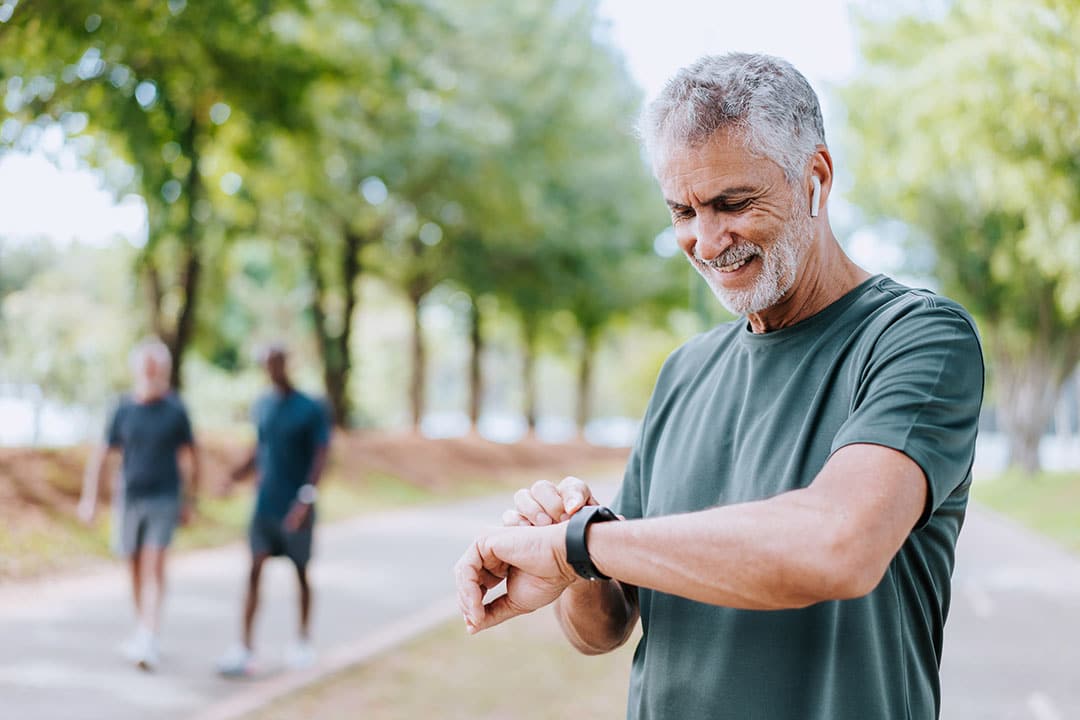 Senior man looking at smartwatch during run - how to lower cholesterol naturally