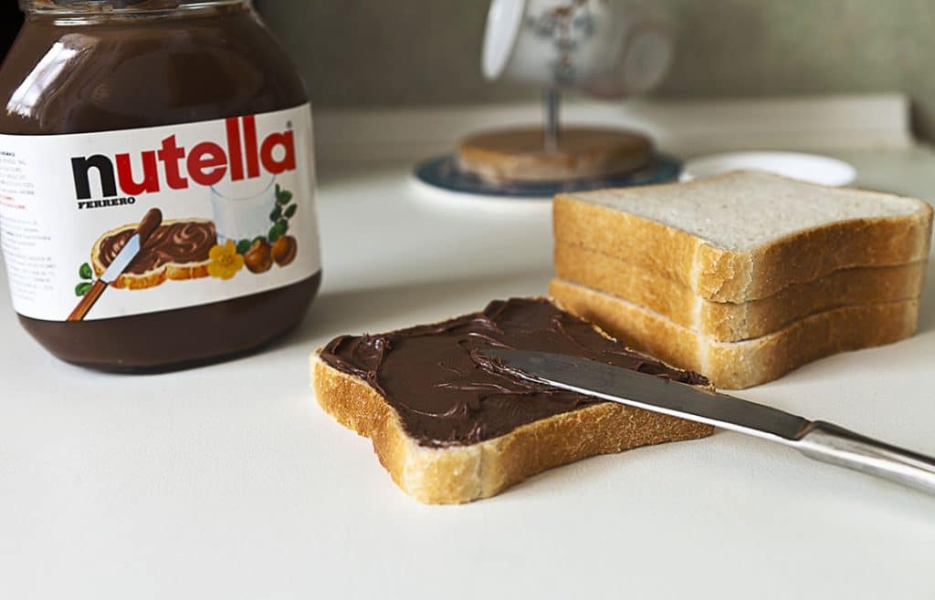 Is Nutella Healthy? Jar of hazelnut butter spread on a piece of bread