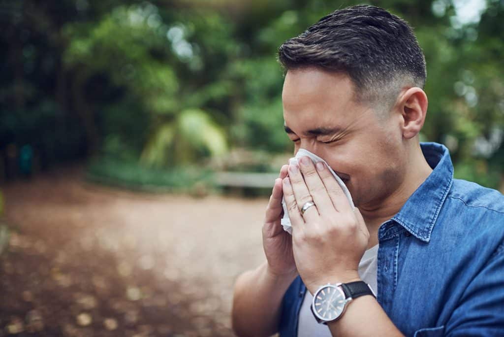 man sneezing outside into a tissue - how to get allergy relief from natural antihistamines