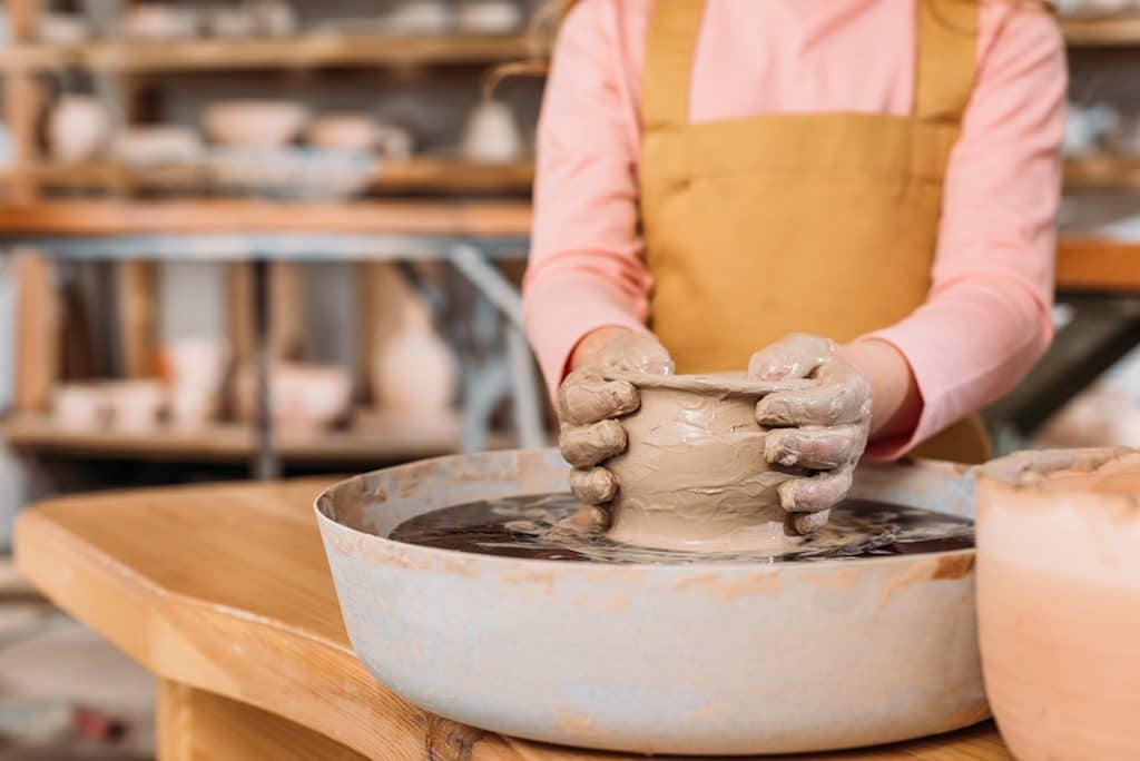 woman making ceramic pot on pottery wheel - fun things to do for yourself