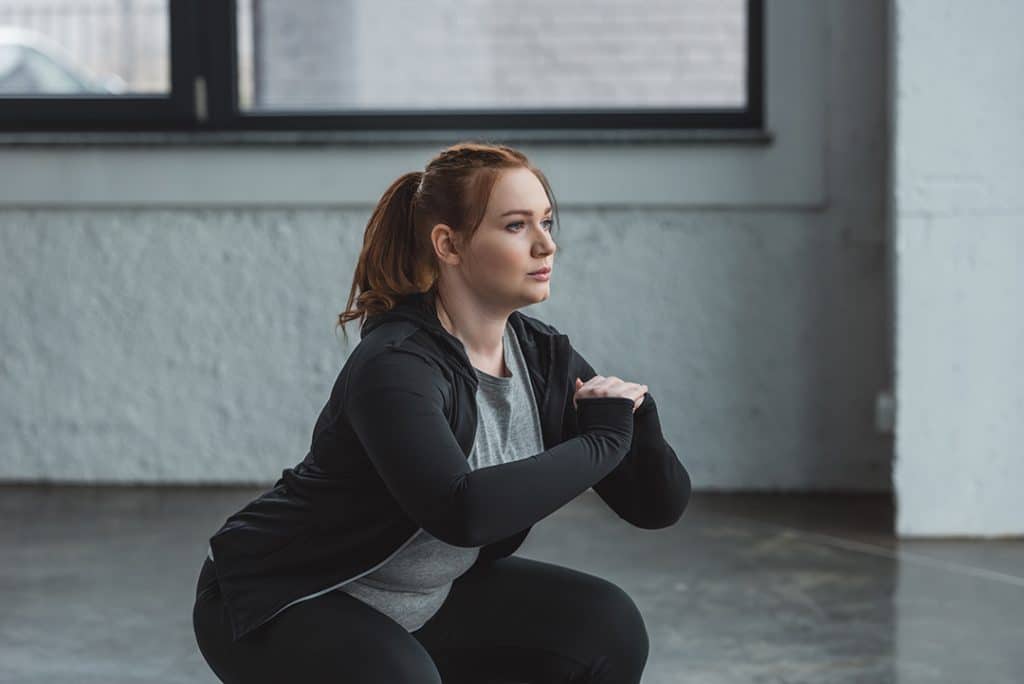 Woman training in sports center using body weight resistance - types of strength training