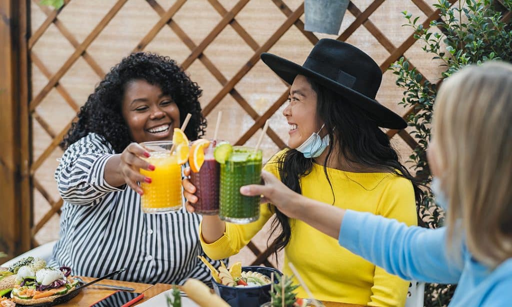 Multiracial friends toasting with fruits fresh smoothies - celebrating healthy habits - cleaning up bad habits