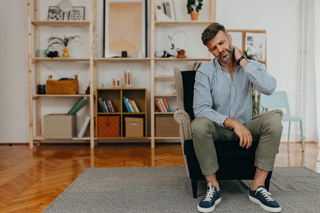 Man rubbing his neck - common causes of neck pain
