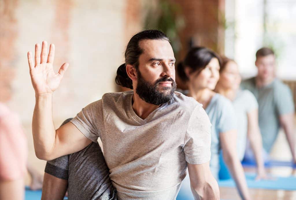 Man working to improve posture with yoga stretches in group class