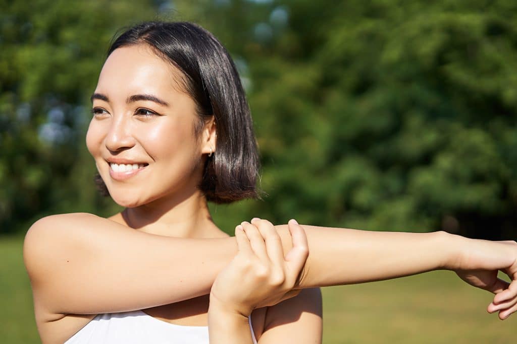 Woman stretching her arms before workout - muscle health