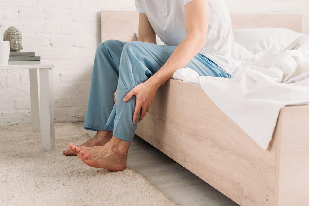 man with leg cramp sitting on couch