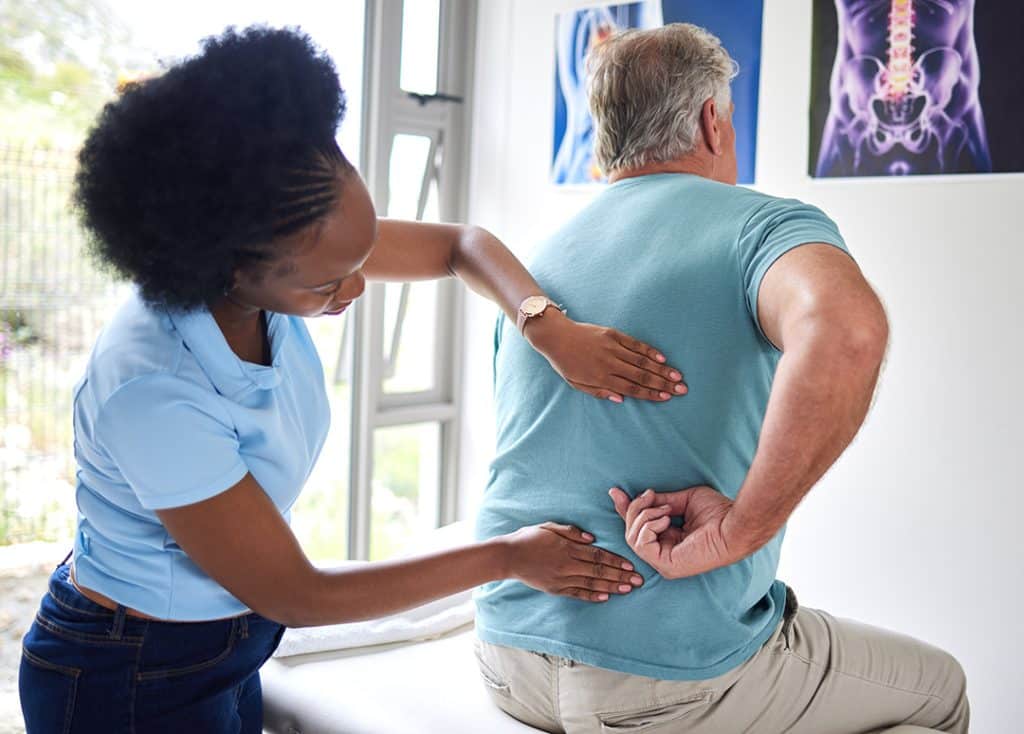 Chiropractor assessing a man's low back mobility and pain