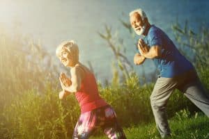 Couple doing yoga outdoors to maintain low back mobility