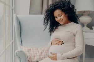 pregnant woman sitting next to window - benefits of chiropractic care during pregnancy
