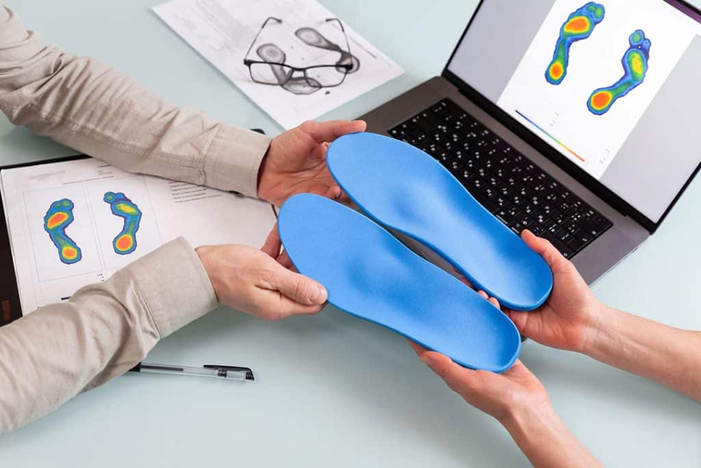 Man getting his custom orthotics from doctor. Digital foot scan review.