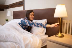 Woman in bed turning off light - sleep hygiene tips