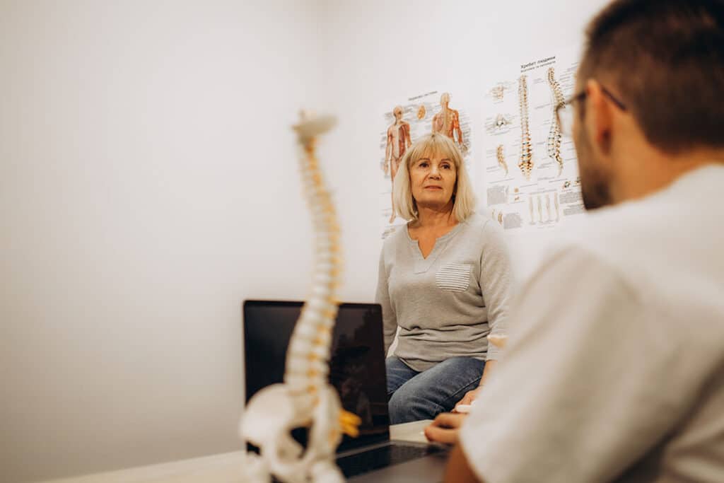 Senior woman talking with chiropractor about spine health and chiropractic for sleep issues