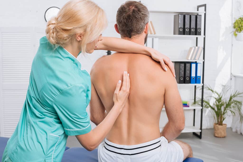 female chiropractor assessing a man's spine and back - chiropractic for sleep issues