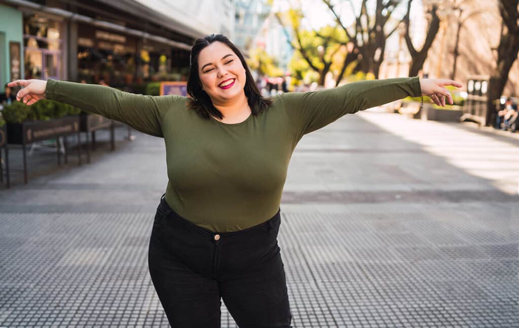 Young plus size woman smiling outdoors in the city - sleep and exercise for weight loss