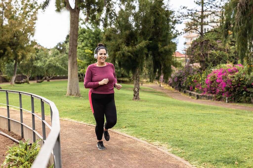 Curvy woman doing jogging routine outdoor at city park - exercise for weight loss