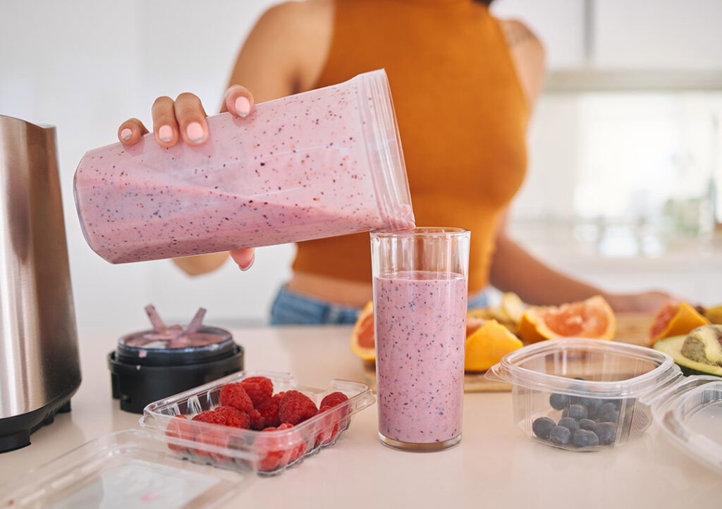 Woman pouring a healthy berry smoothie into a glass - immune boosting habits