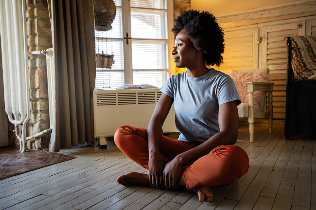 young black female meditating indoors - benefits of reduced screen time