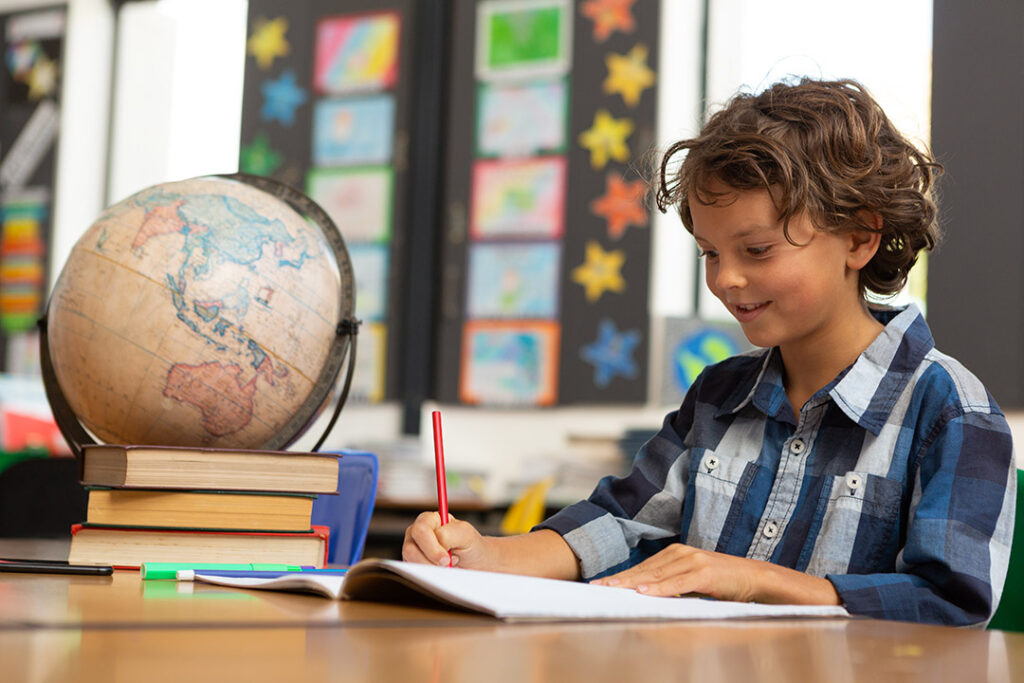 Boy happily studying at a desk - benefits of reduced screen time - focus in school