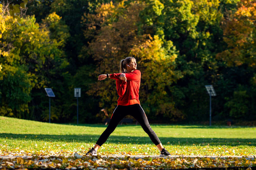 Young woman warming up and stretching before running in park. Immune boosting lifestyle