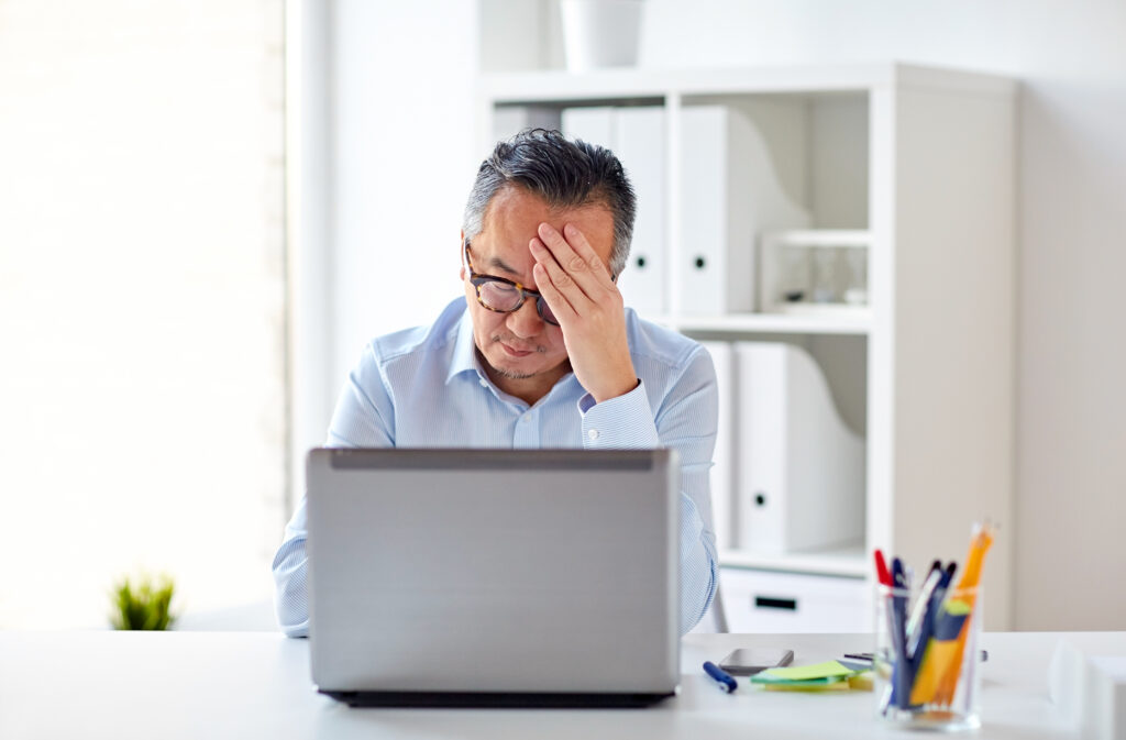 businessman in eyeglasses with laptop at office - stressed out