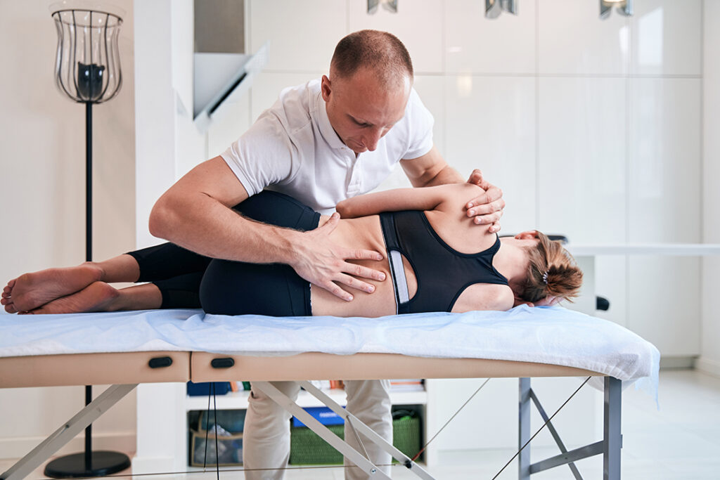 Woman lying on side being adjusted by a chiropractor - chiropractic for constipation