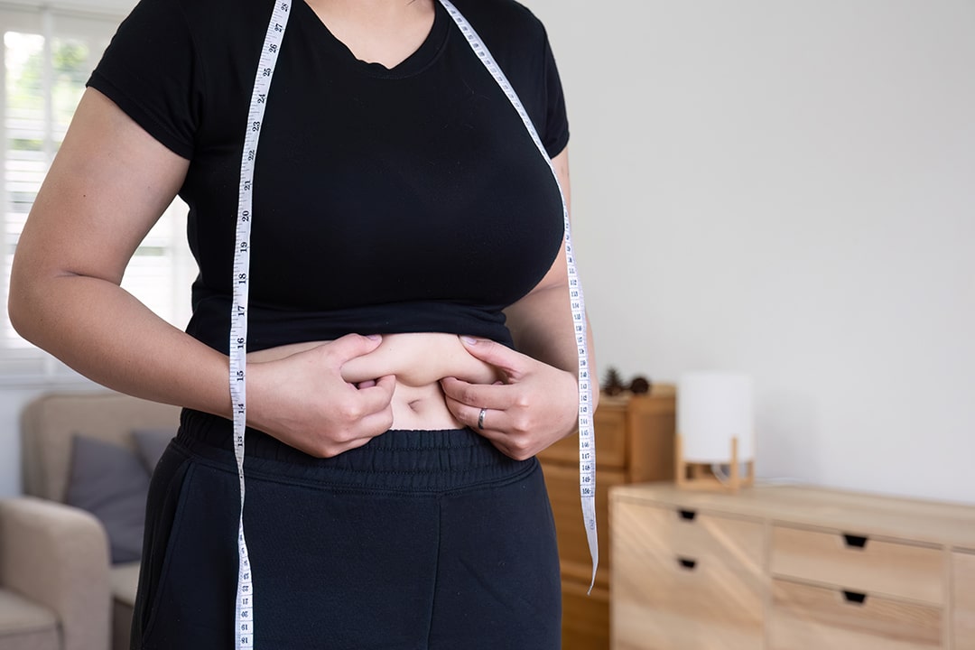 Woman pinching extra weight around her waist - stress and weight gain