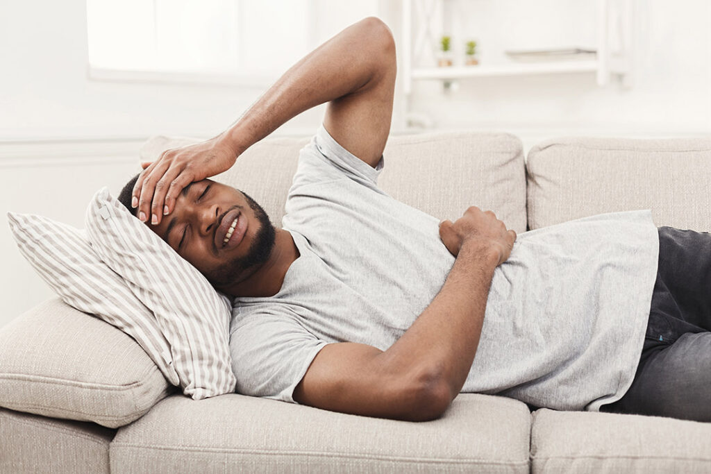 Man on couch stressed with digestive issues