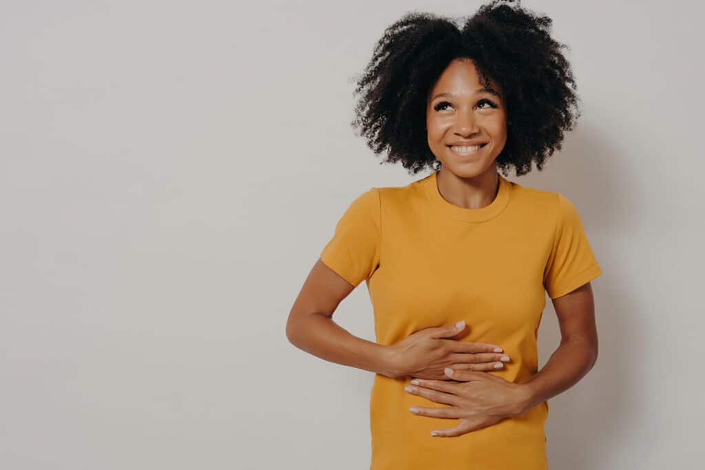 Happy woman holing her stomach thanks to improved digestion