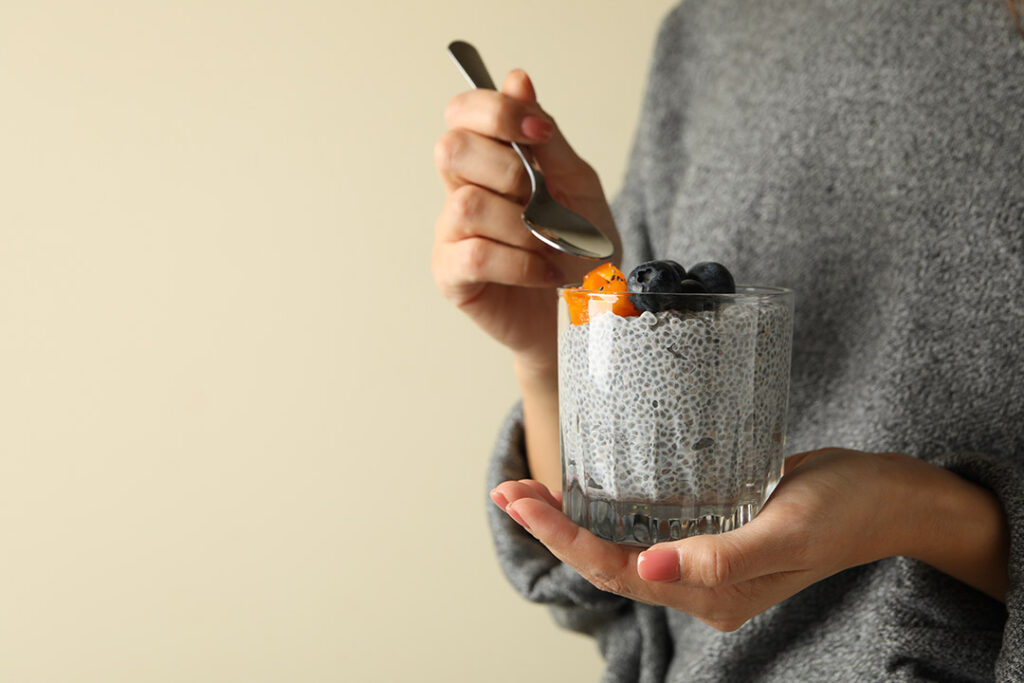 Woman eating chia seed pudding with fruit on top