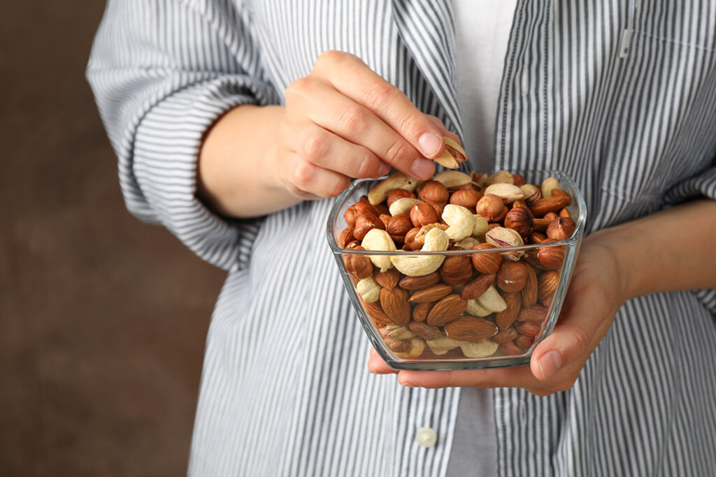 Woman holding a bowl of nuts - health snacks to help with stress and weight gain