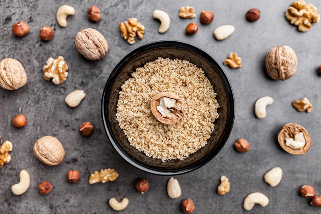 Oats in a bowl with walnuts and other nuts in the background - heart healthy foods