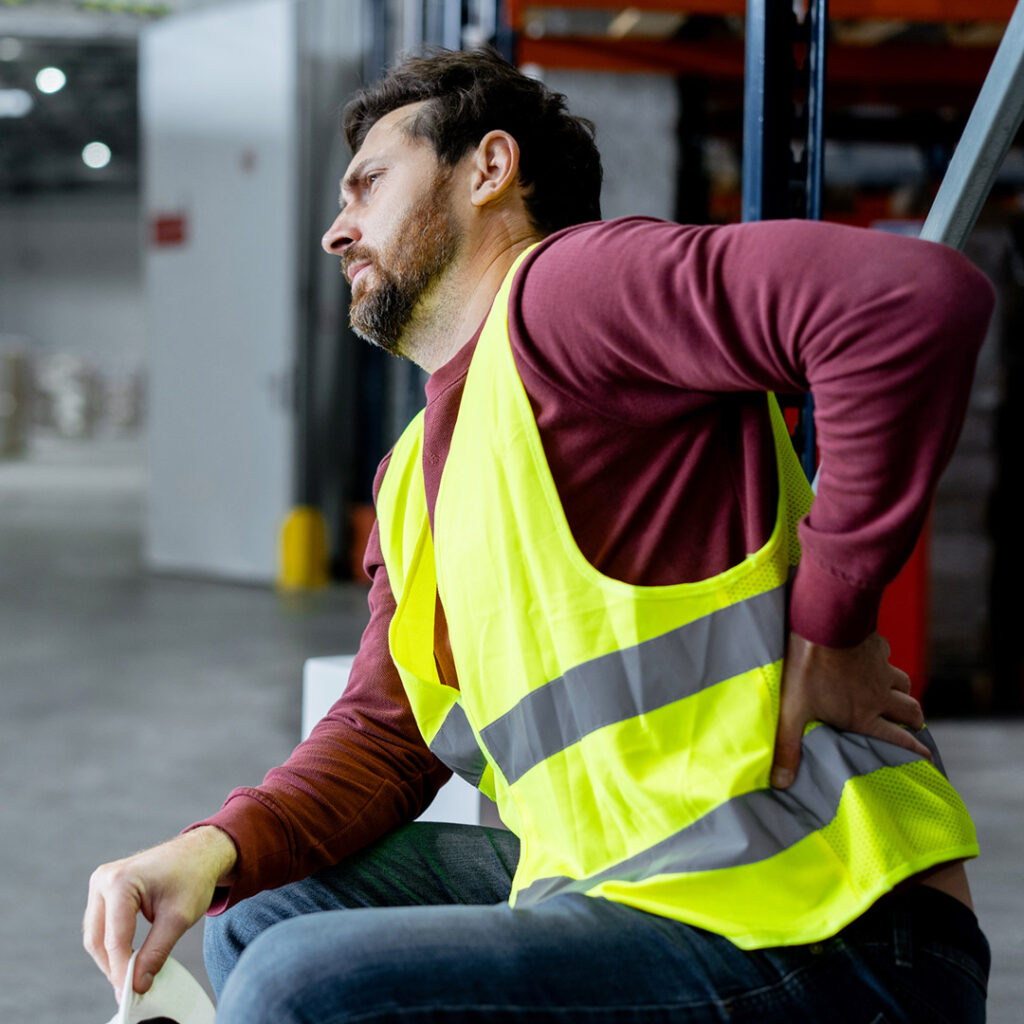 Man wearing construction vest holding back in pain - personal injury back pain chiropractor