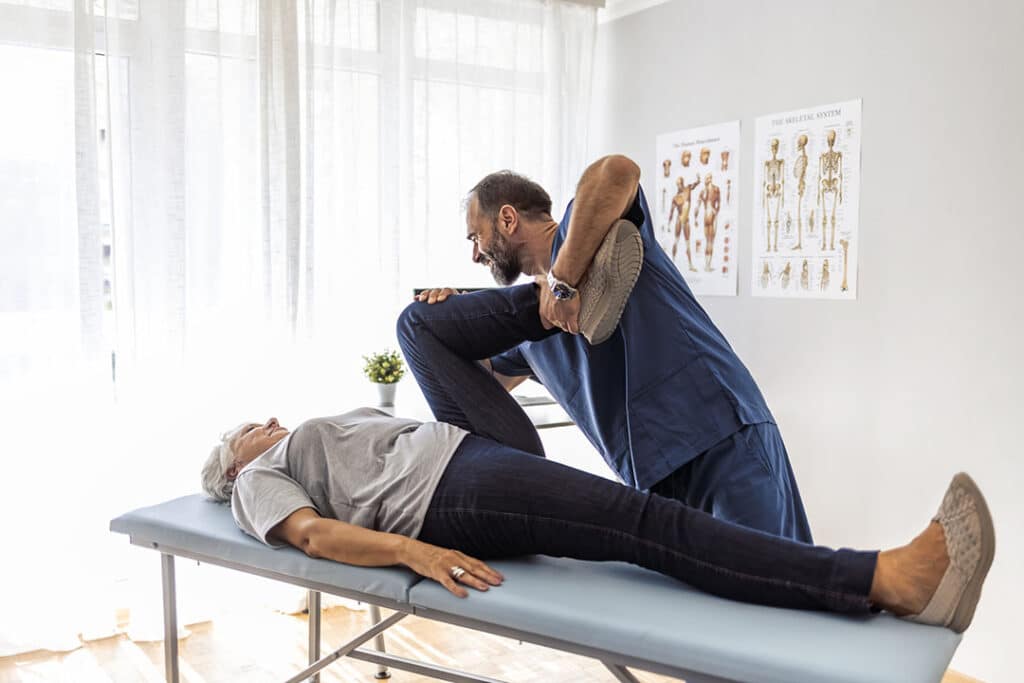 Chiropractor adjusting woman's leg and back