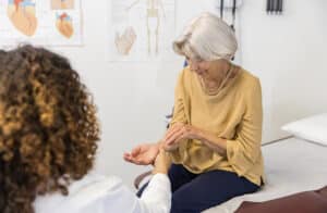 woman with carpal tunnel or repetitive strain injury RSI talking with doctor