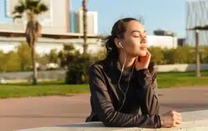 Person resting outdoors with eyes closed and earphones in